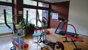 Un gimnasio con diversos equipos de ejercicio, incluyendo cinta de correr, elíptica y máquinas de pesas.