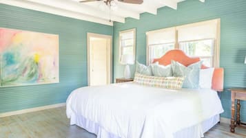 Une chambre avec des murs de couleur turquoise, un lit blanc et un grand tableau abstrait.
