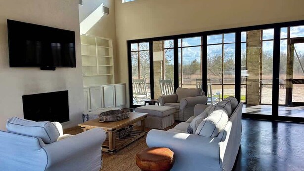 A spacious living room with a large window, a flat-screen TV, and a fireplace.