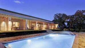 A poolside area with a covered patio, a clear pool, and a stone border.