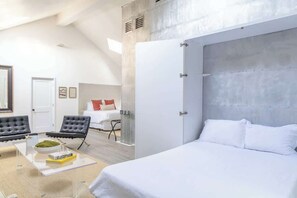 A modern bedroom with a large bed, a seating area with a coffee table, and a view of the room's interior.