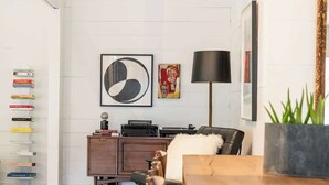 A modern dining area with a wooden table, chairs, a wicker ceiling light, a black floor lamp, and a bookshelf with books. - 2 King Beds+Grill+Pool | 6 Min. To Round Top (Round Top)