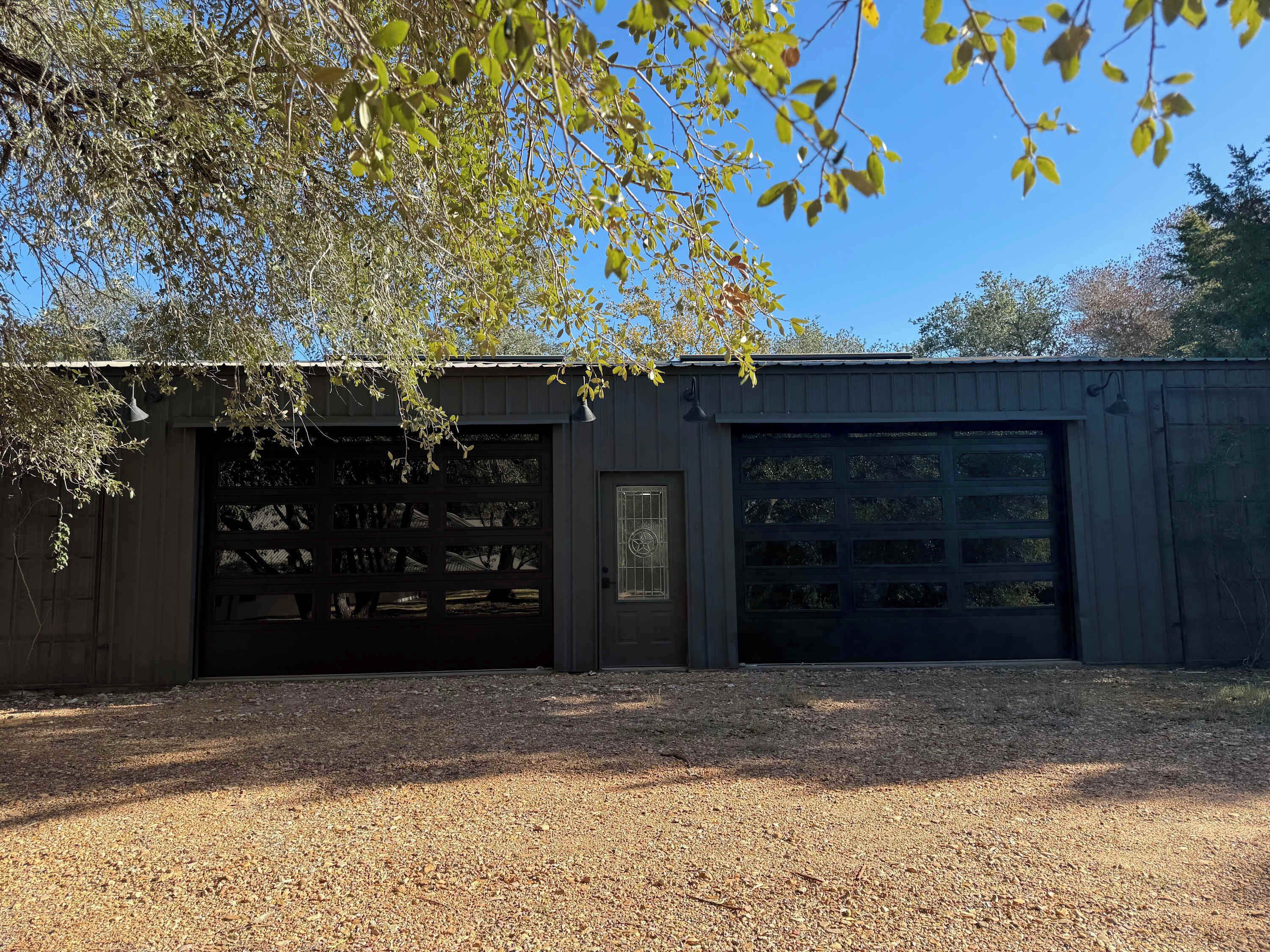 A single-story building with a dark exterior, a garage with multiple doors, and a small door with a decorative window.