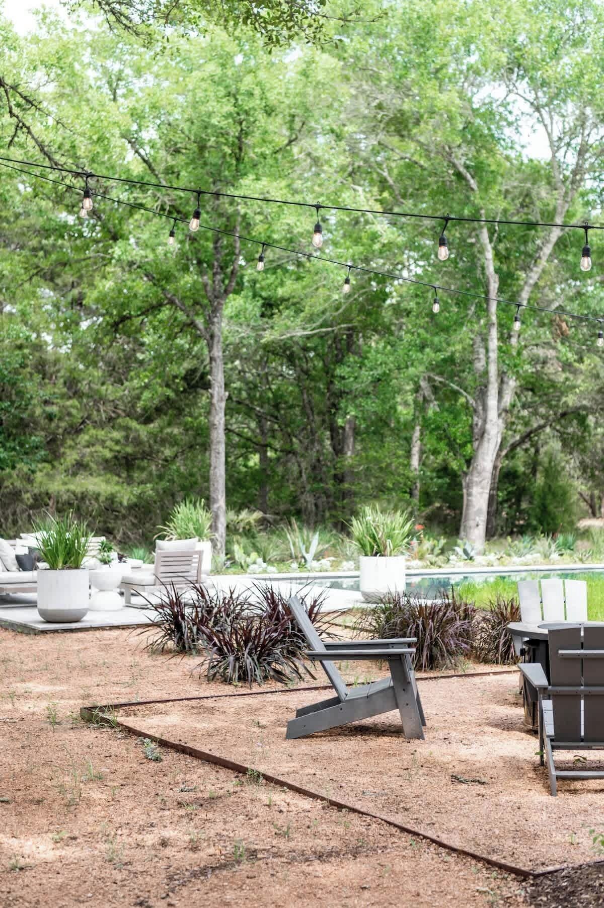 An outdoor seating area with modern chairs and tables, surrounded by greenery and trees.