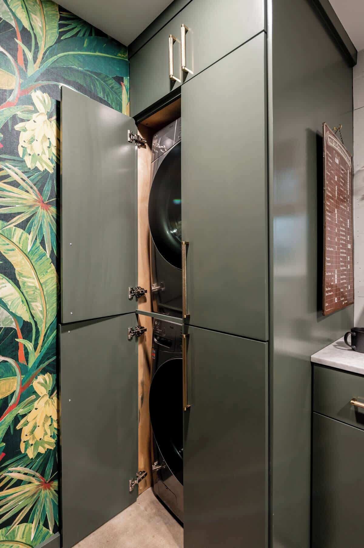 A compact, modern bathroom with a built-in washer and dryer, a wooden cabinet, and a decorative wall mural.