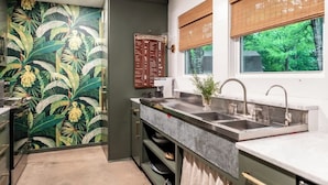 A kitchen with a tropical-themed wallpaper, a built-in sink, and a window with blinds. - 2 King Beds+Grill+Pool | 6 Min. To Round Top (Round Top)