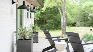 An outdoor patio with two Adirondack chairs, a table, and two potted plants. - 2 King Beds+Grill+Pool | 6 Min. To Round Top (Round Top)