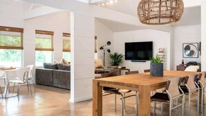 A modern living room with a wooden dining table, comfortable seating, a large TV, and a wicker ceiling light. - 2 King Beds+Grill+Pool | 6 Min. To Round Top (Round Top)