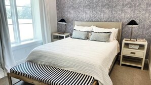 A neatly arranged bedroom with a bed, bedside tables, and a bench.