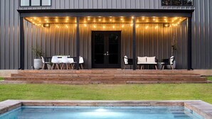 A modern house with a pool, outdoor seating, and string lights.