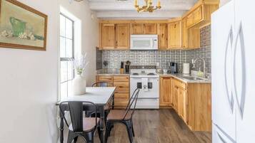 A kitchen with wooden cabinets, a white refrigerator, a stove, and a dining table with chairs.