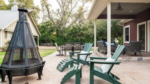 Een terras met Adirondack stoelen, een vuurkorf en een overdekte zithoek.
