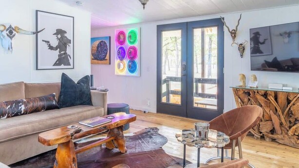 Una sala de estar acogedora con una mesa de centro de madera, un sofá con cojines estampados, una mesa baja de vidrio y un aparador rústico.