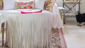 A bedroom with a bed, two windows, a chandelier, a mirror, and a small table with glasses. - Wine, Dine, & Unwind | Stay in Style + Shop RT (Carmine)