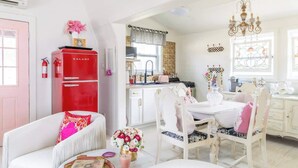 A bright, well-lit room with a white sofa, a dining table with chairs, a red refrigerator, and a chandelier. - Wine, Dine, & Unwind | Stay in Style + Shop RT (Carmine)