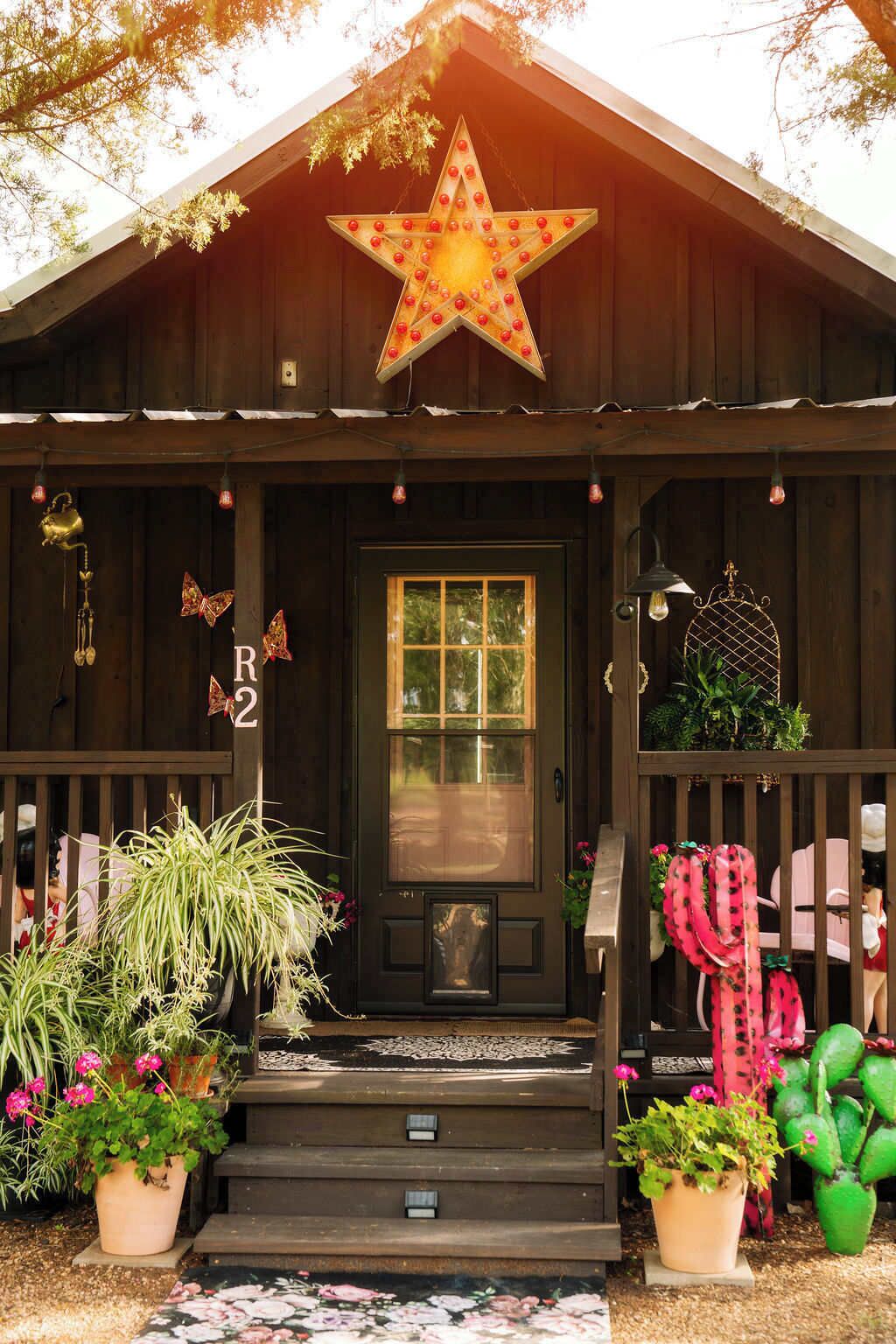 A wooden cabin with a star decoration, a mailbox, and potted plants.