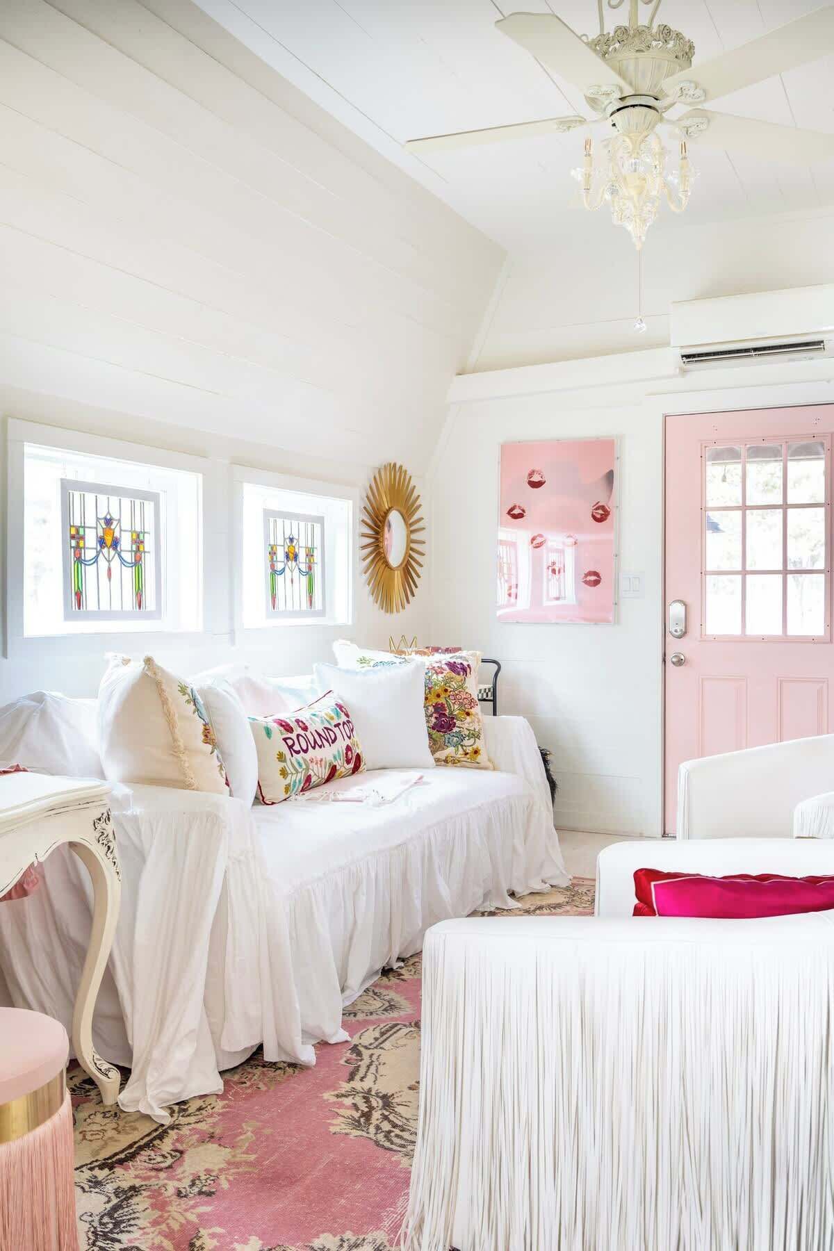 A bedroom with two beds, a chandelier, a pink door, and a decorative mirror.