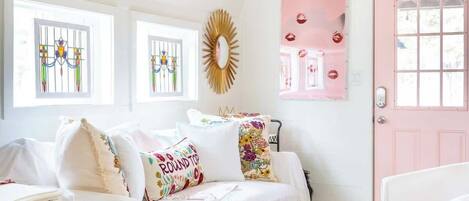 A bedroom with two beds, a chandelier, a pink door, and a decorative mirror.