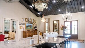 Una cocina amplia con encimera de mármol, un lavabo y una araña.