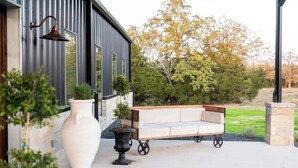 Exterior moderno con un gran jarrón blanco, un sofá con ruedas y un aplique de pared.
