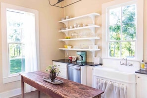 Una cocina con estantes blancos, una cafetera y un lavabo.