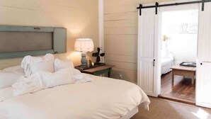 Un dormitorio con cama, mesita de noche con lámpara, puerta corrediza a un balcón y suelo de madera.