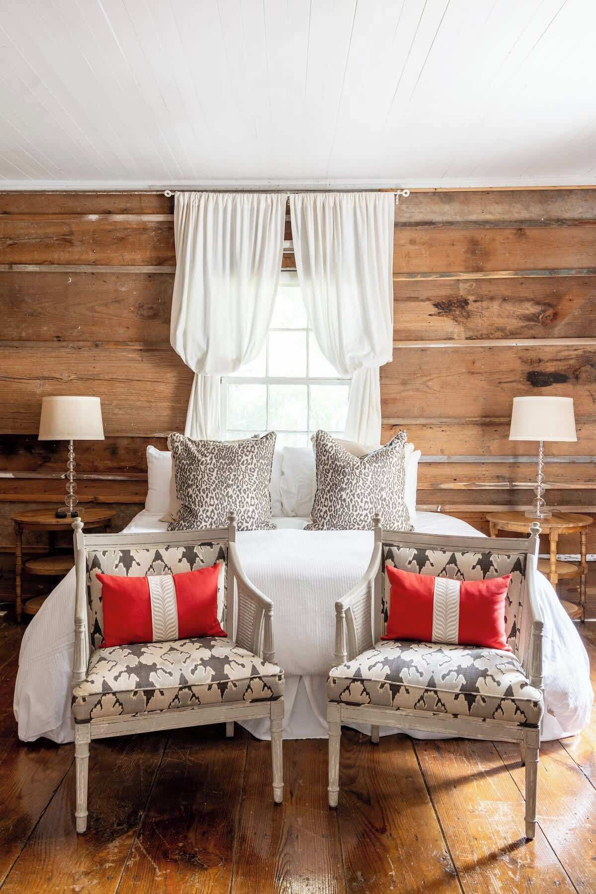 Una habitación acogedora con una cama, dos sillones, una mesita y dos lámparas.