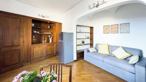 A living room with a wooden cabinet, a blue sofa, and a refrigerator. - Maison Giulia (Rome)