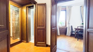 A hallway with wooden doors leading to a dining area with a table and chairs. - Maison Giulia (Rome)