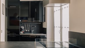 Una cocina moderna con armarios negros, una campana de acero inoxidable y una isla de vidrio.