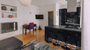 Una sala de estar moderna con chimenea, un comedor y una cocina con barra.