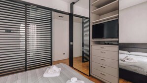 Un dormitorio moderno con cama, televisor y armario.