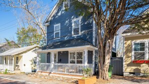 A two-story house with a porch, a tree in front, and a small garden bed. - Wilmington's Heart, Pet-Friendly, Comfy Beds, Kids room! (Wilmington)
