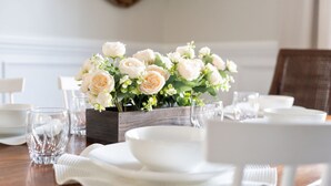 A dining table set with white plates, bowls, and glasses, accompanied by a floral centerpiece. - Wilmington's Heart, Pet-Friendly, Comfy Beds, Kids room! (Wilmington)