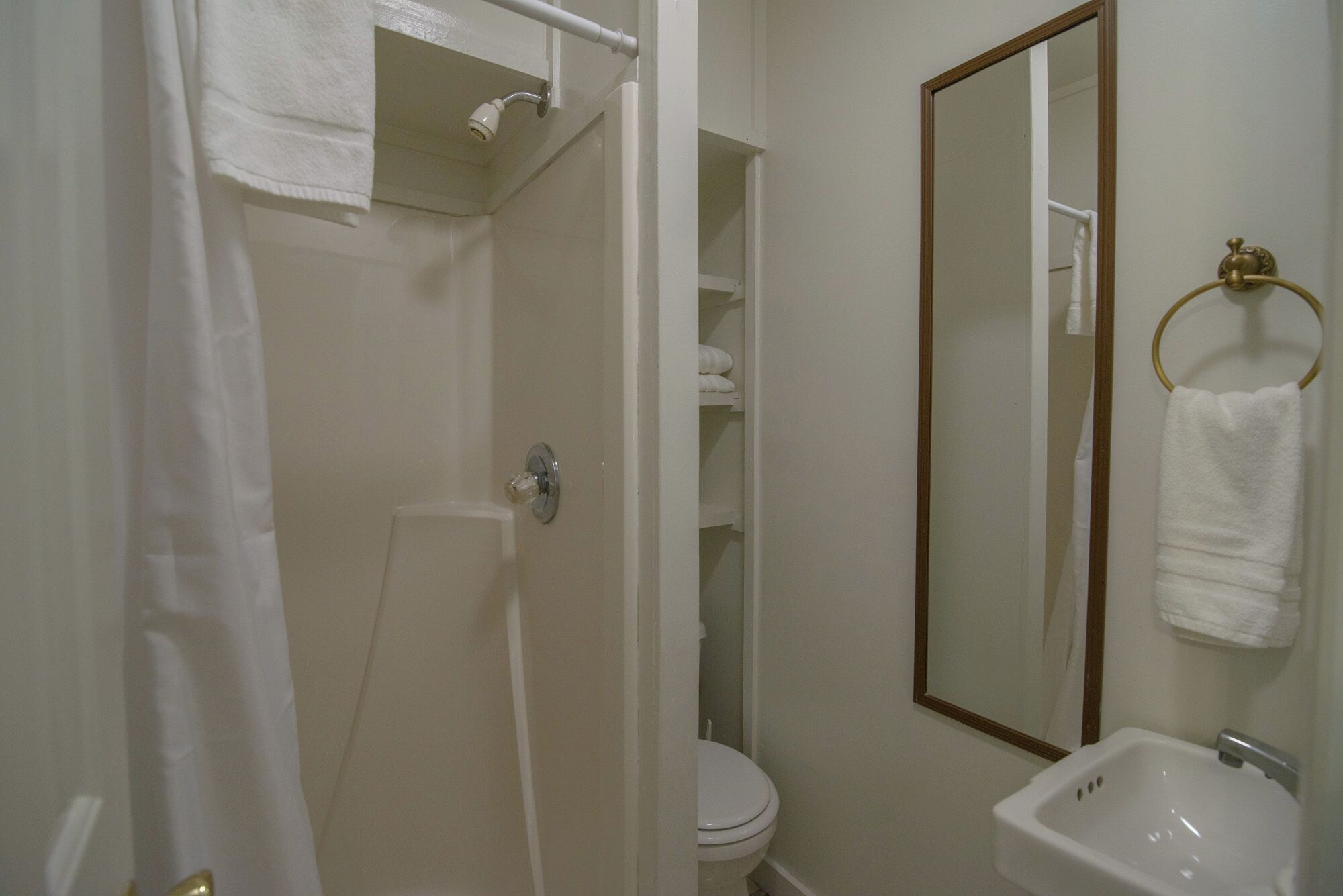 Un baño con ducha, inodoro, lavabo y espejo.