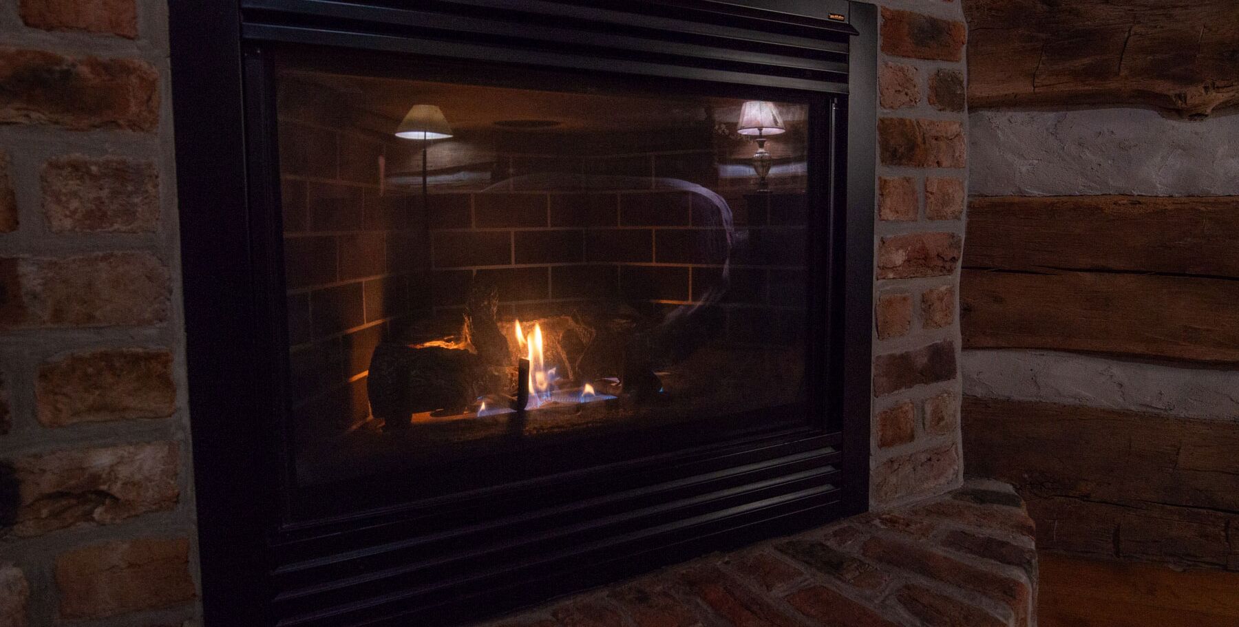 A fireplace with a visible fire, set in a brick wall.