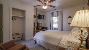 A bedroom with a bed, a ceiling fan, a TV, a dresser, and a chair.