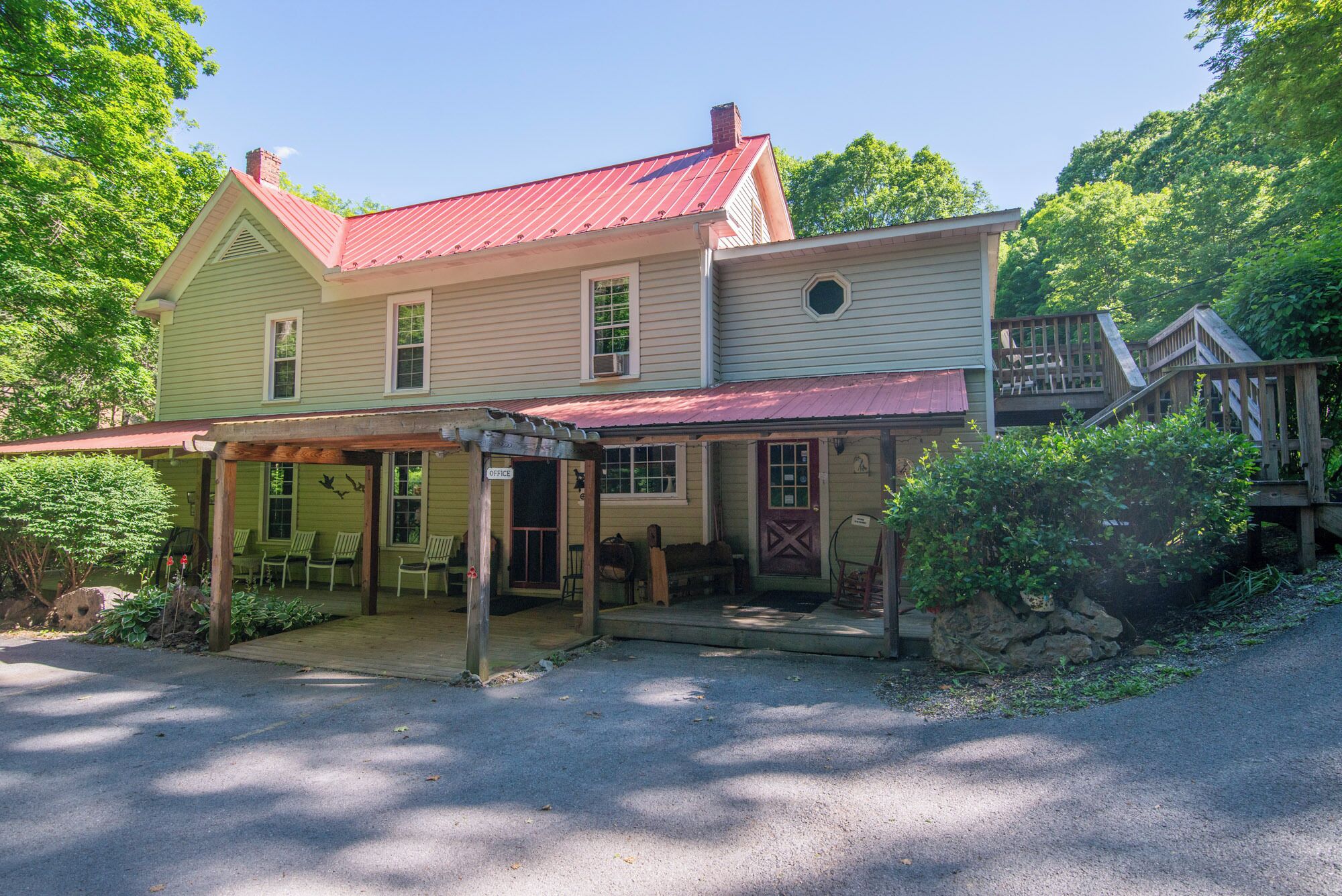 A two-story building with a red roof and a covered porch area.