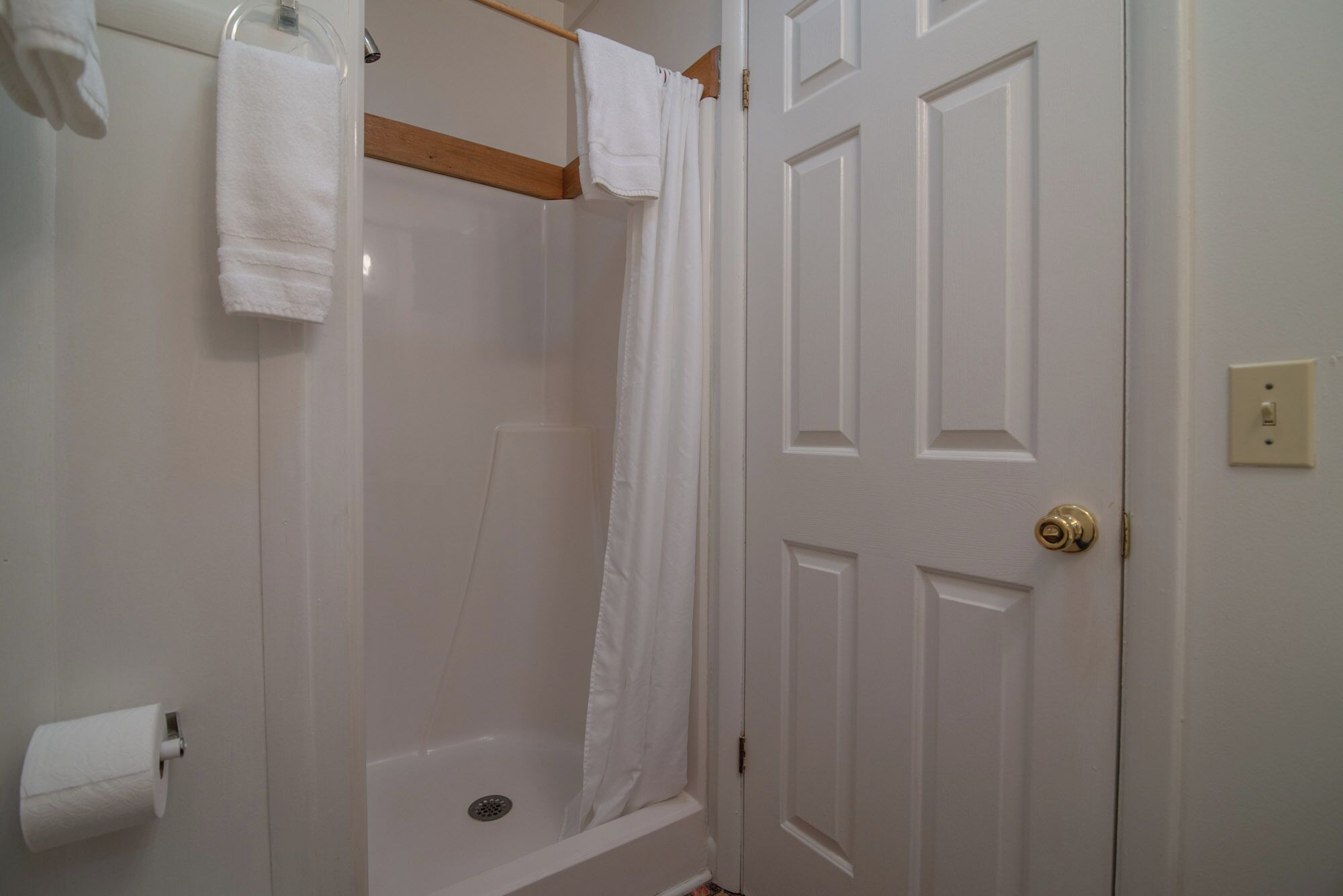A bathroom with a shower, a toilet, and a door.