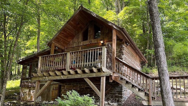 A rustic cabin with a wooden balcony, surrounded by trees. - Moore House Inn & Cabins (Marlinton)