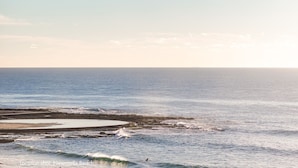 Un paysage côtier avec une plage, des vagues et une jetée.