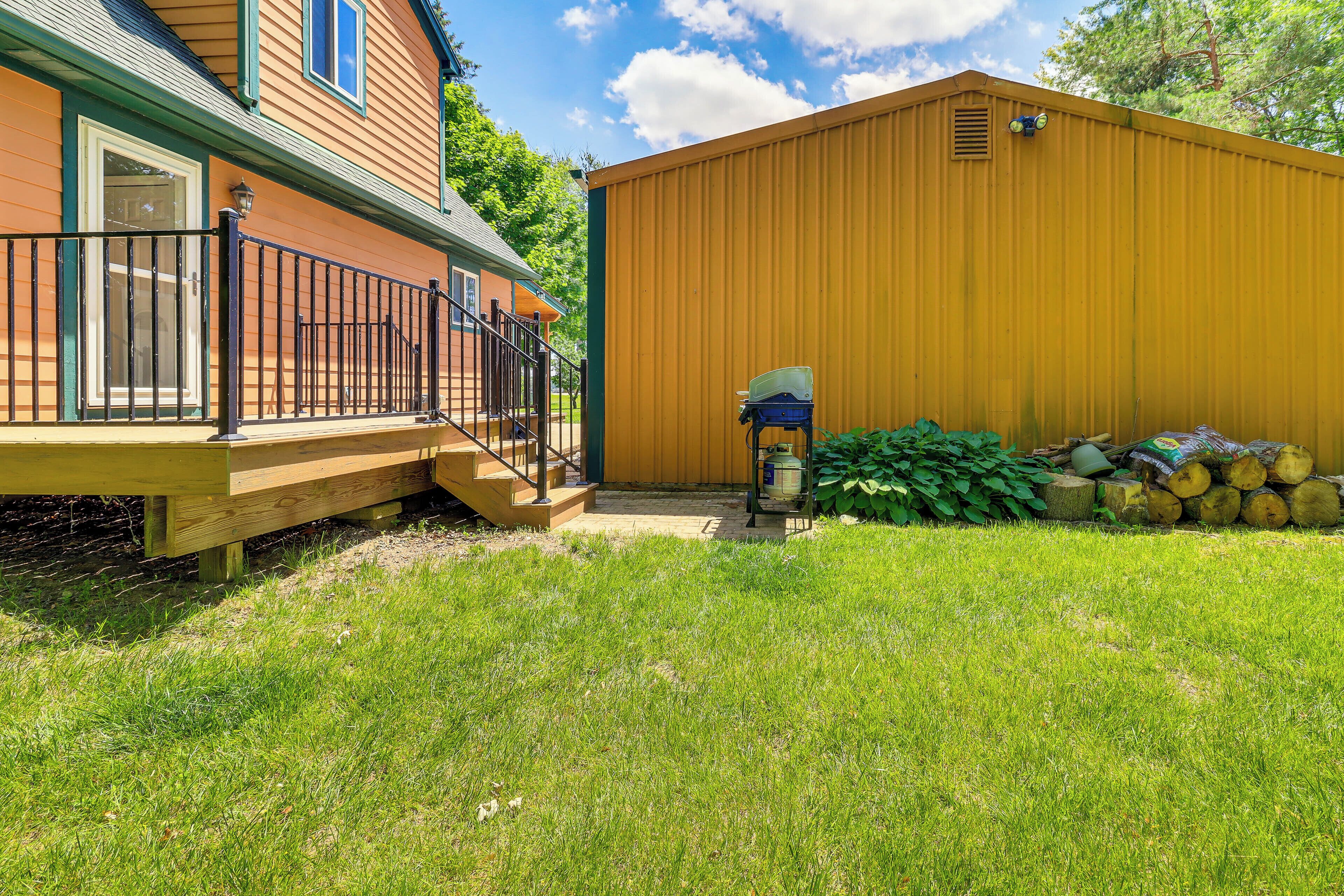 A wooden house with a covered porch and a yellow shed.