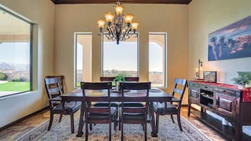 A dining area with a chandelier, a large window, and a view of the landscape.