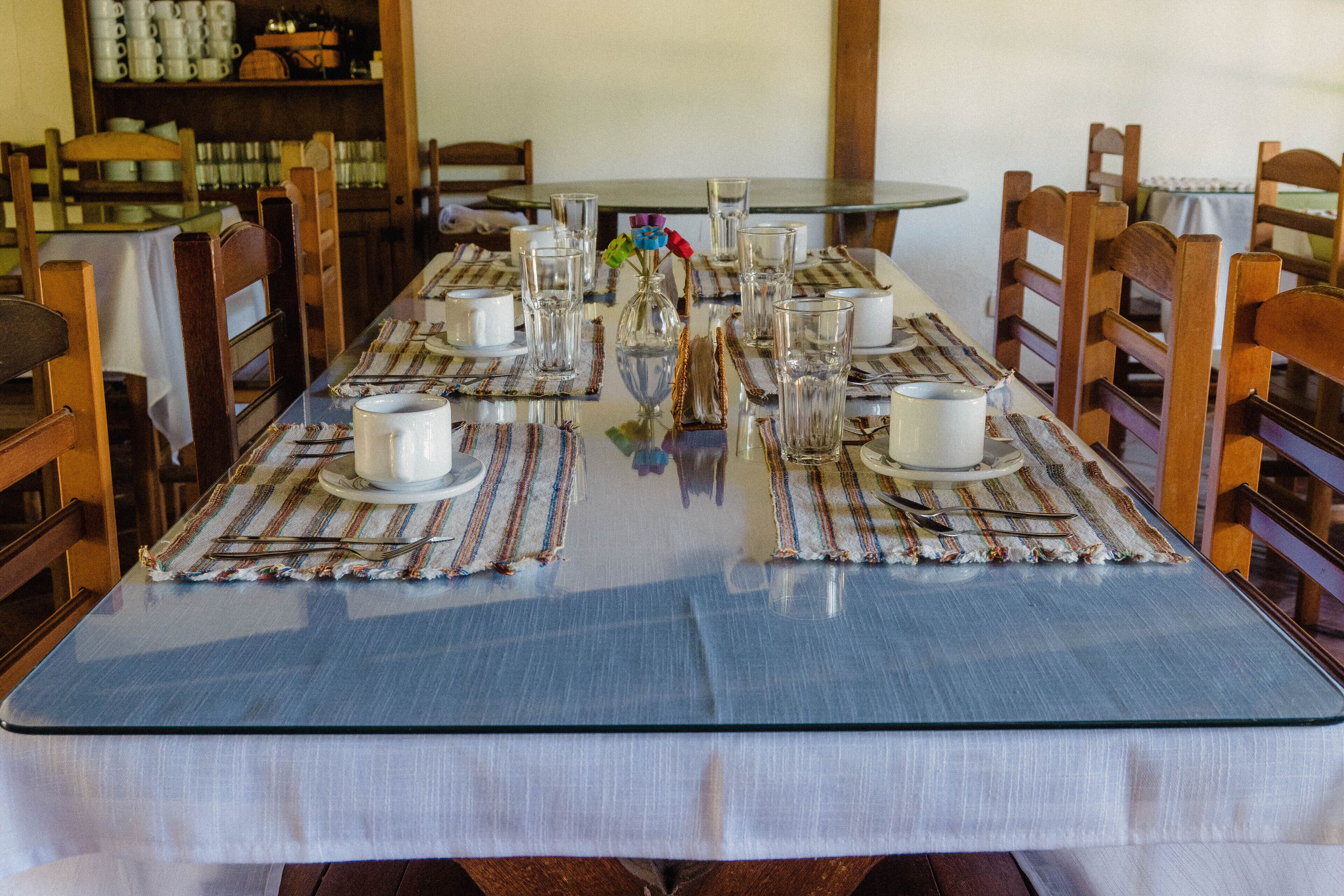 A dining table set with white cups, clear glasses, and a striped placemat.