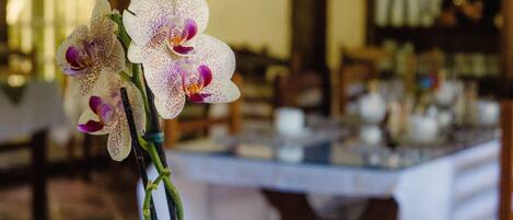 Un tavolo apparecchiato con tovaglie bianche e un vaso con orchidee bianche.