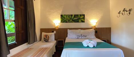 Ett hotellrum med två separata sängar, en stor säng, en takfläkt, en väggmonterad lampa, en grön väggdekoration och ett klinkergolv.