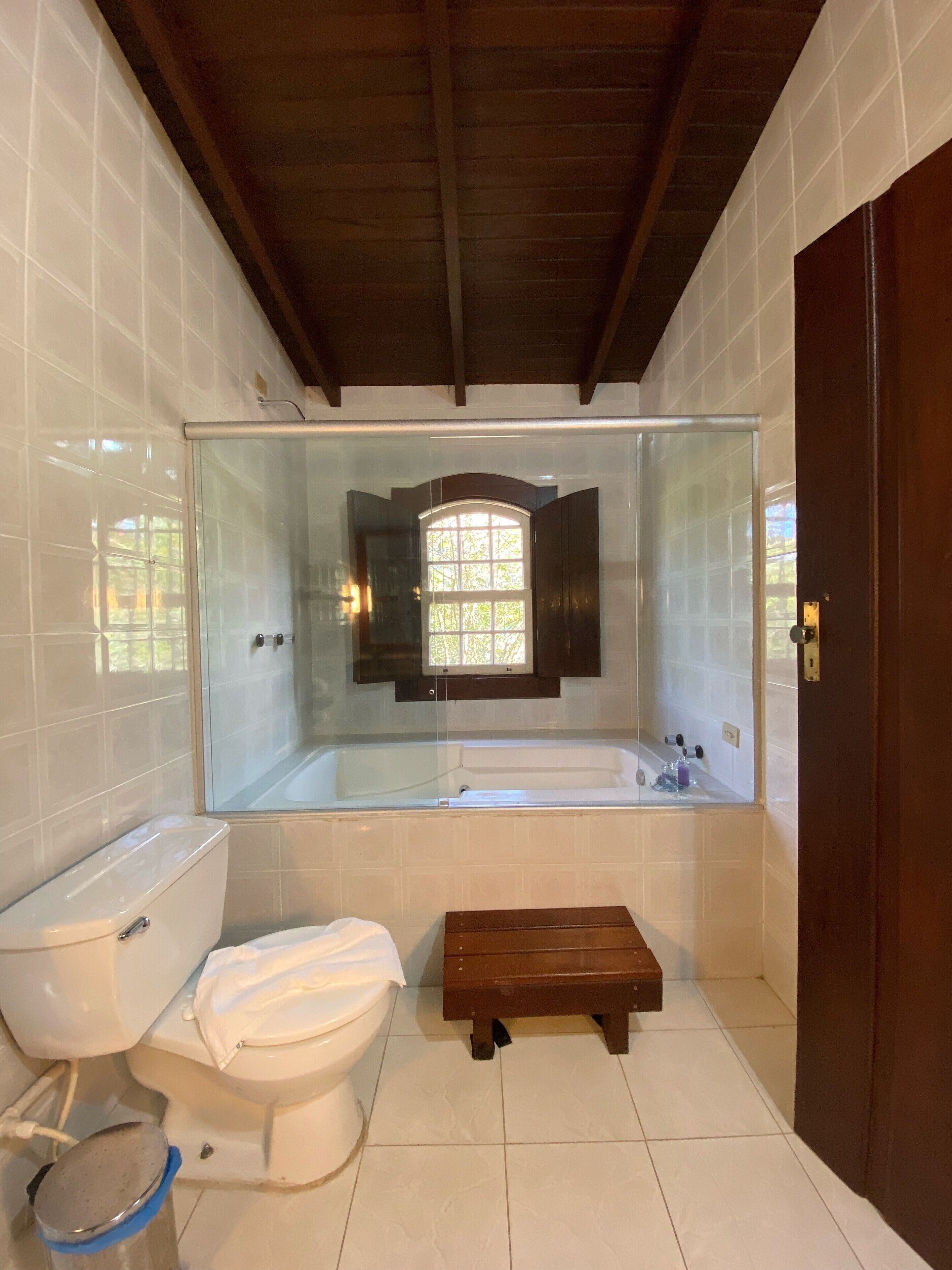 Un bagno moderno con doccia vetrata, un water bianco e una panca in legno.