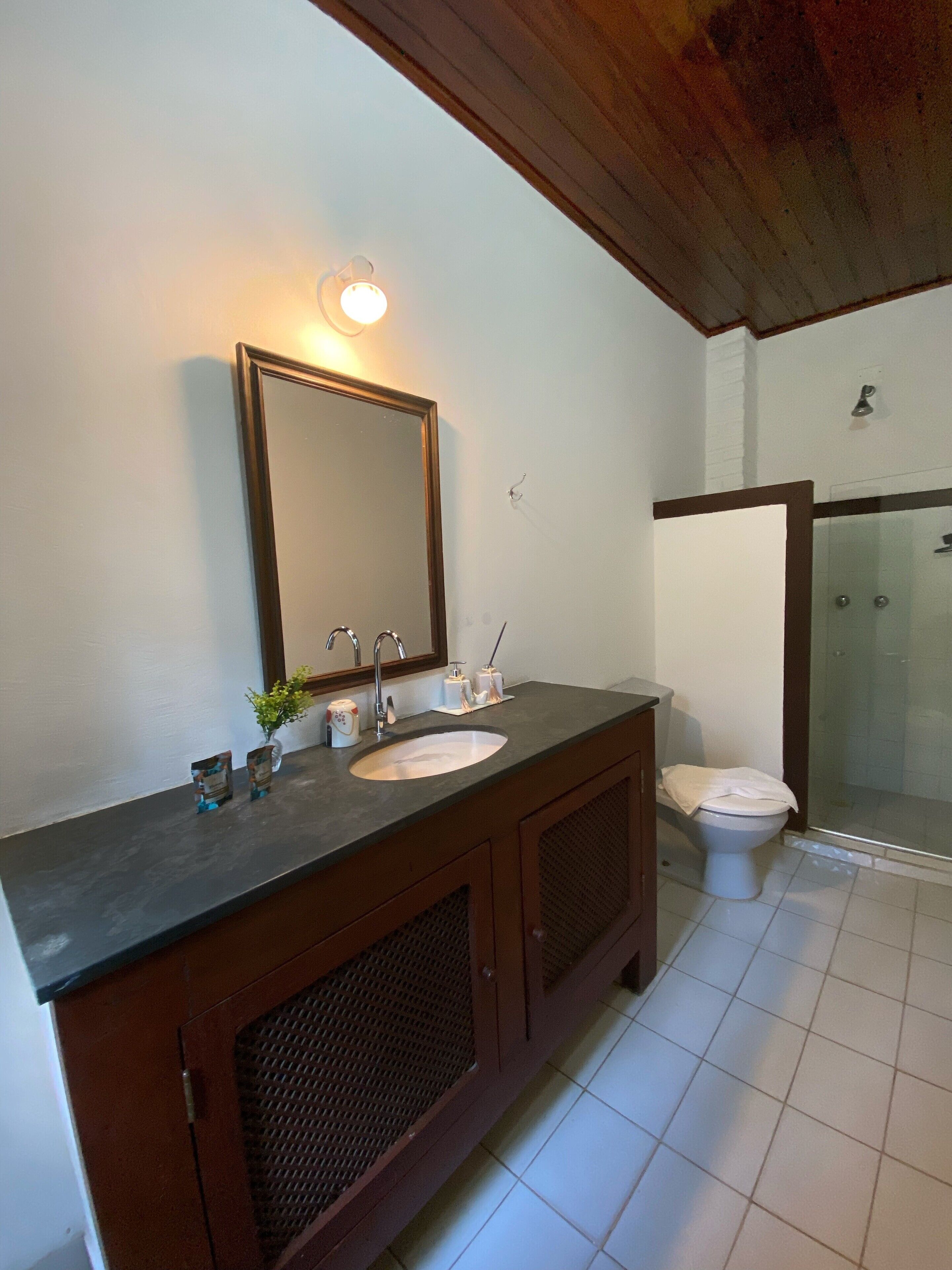 A bathroom with a wooden vanity, a large mirror, a sink, a toilet, and a glass shower enclosure.