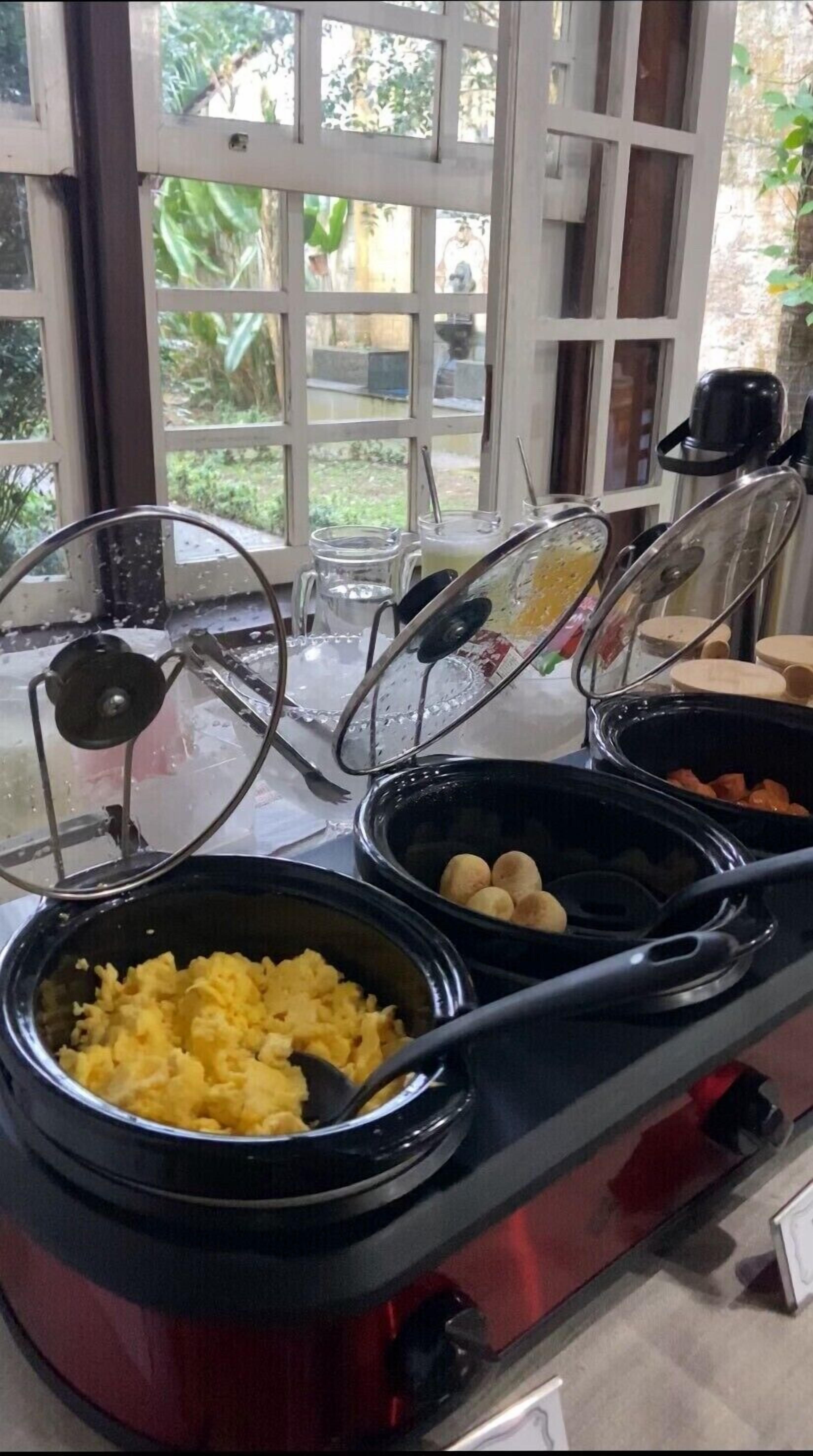 A buffet setup with various food items including scrambled eggs, mushrooms, and a soup.