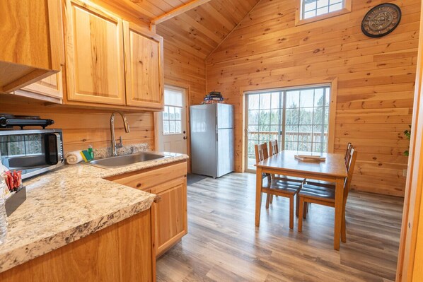 Interior de madera con cocina, encimera de granito y mesa de comedor con sillas.